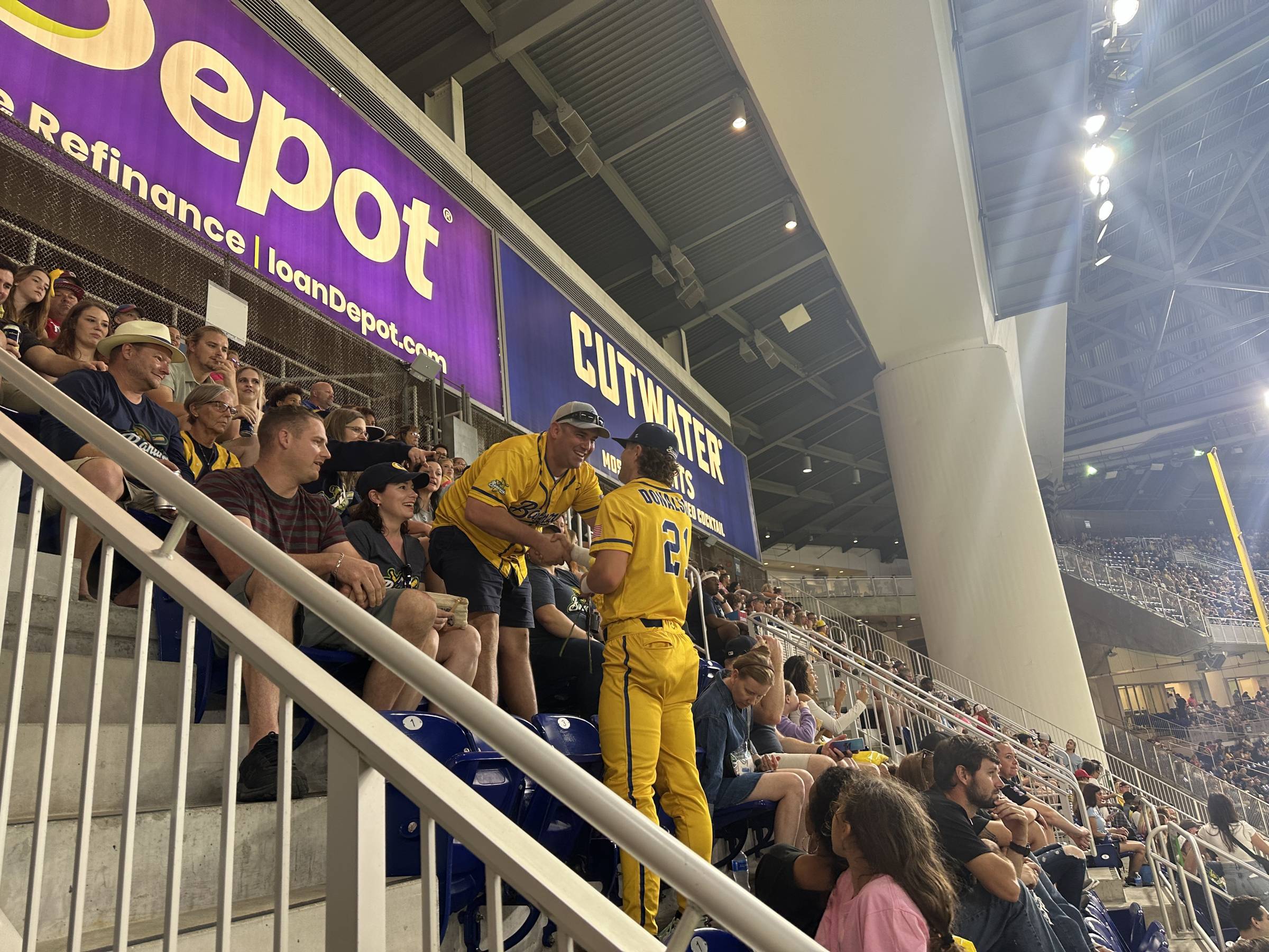 Savannah Bananas player greets a fan in the stands of loanDepot Park.